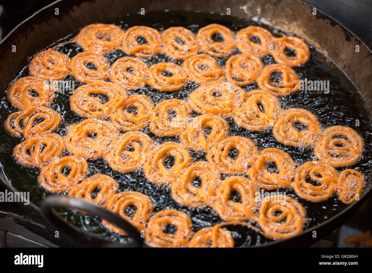 Close-up of delicious jalebis frying in oil pan at stall Stock Photo