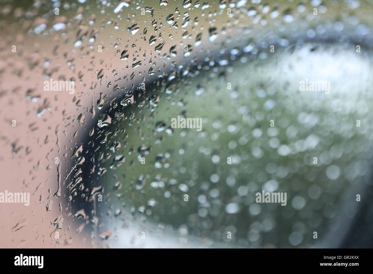 Wet Car Side Mirror. Side mirror of a car through the windshield in the rain. Rain drops on the car glass window. Stock Photo