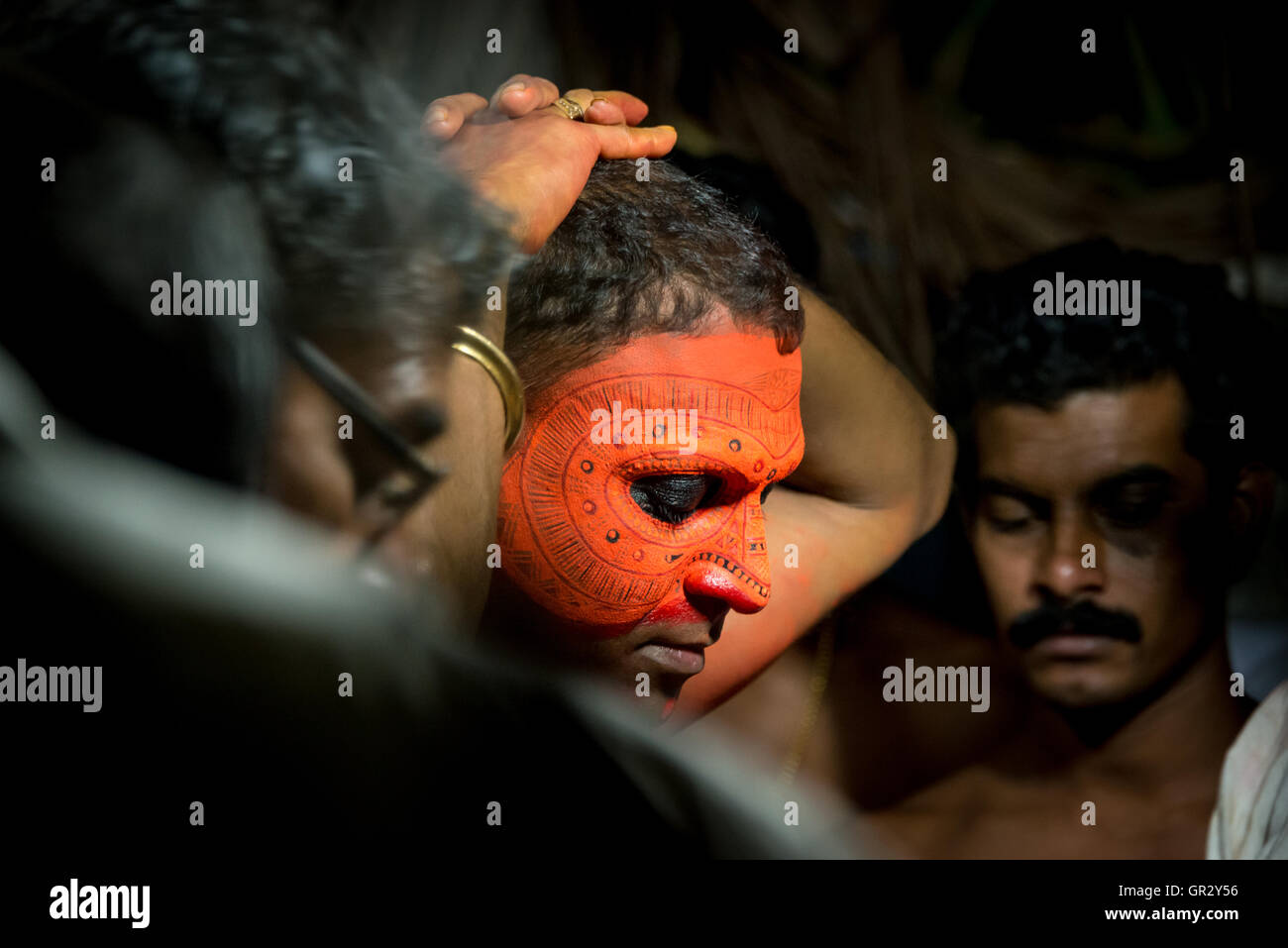 Make up and costume being applied to transform a man in to a deity  for the Theyyam ritual at a village near Kannur, Kerala Stock Photo