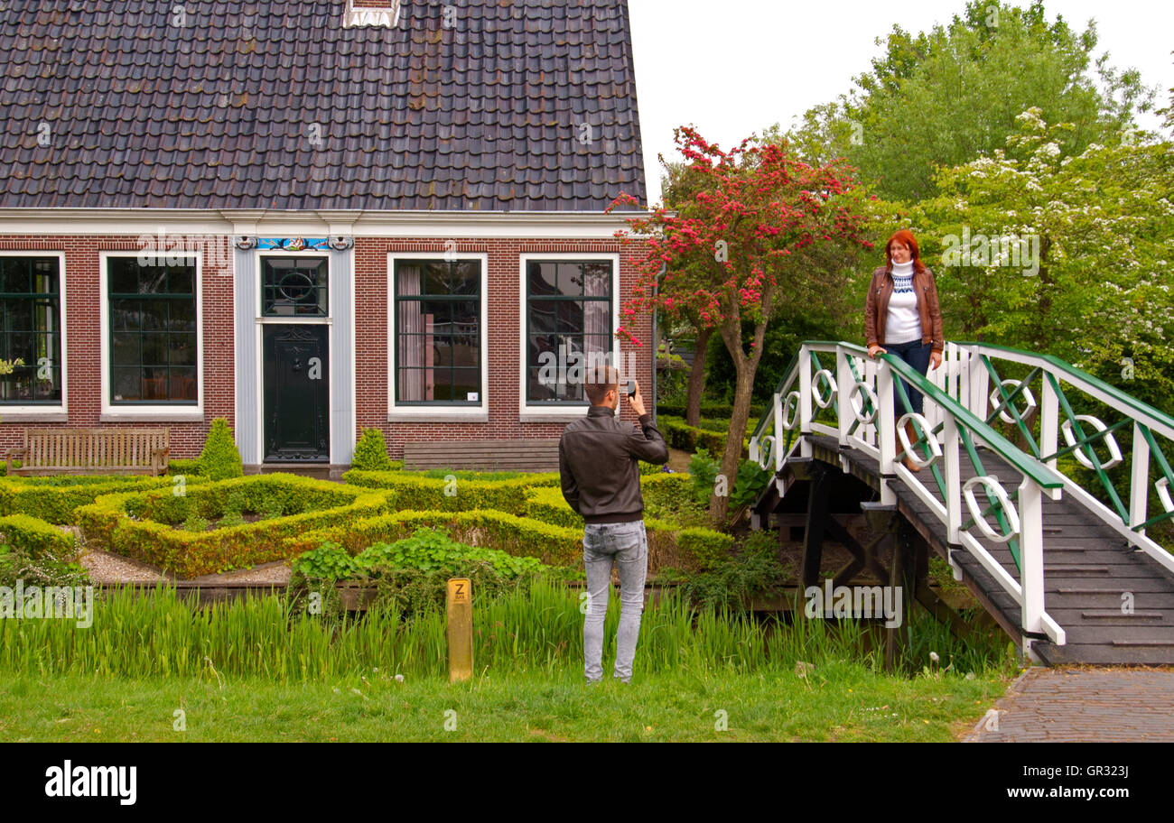 Woman poses for photographer on bridge to typical restored Dutch house moved to Zaanse Schans, Zaandam, Holland Stock Photo