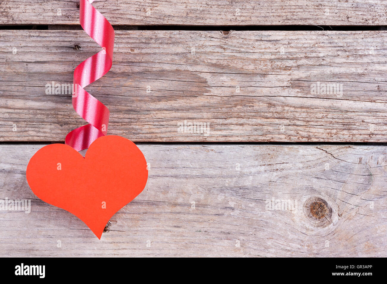 Red paper heart hanging from a ribbon on wooden background Stock Photo ...