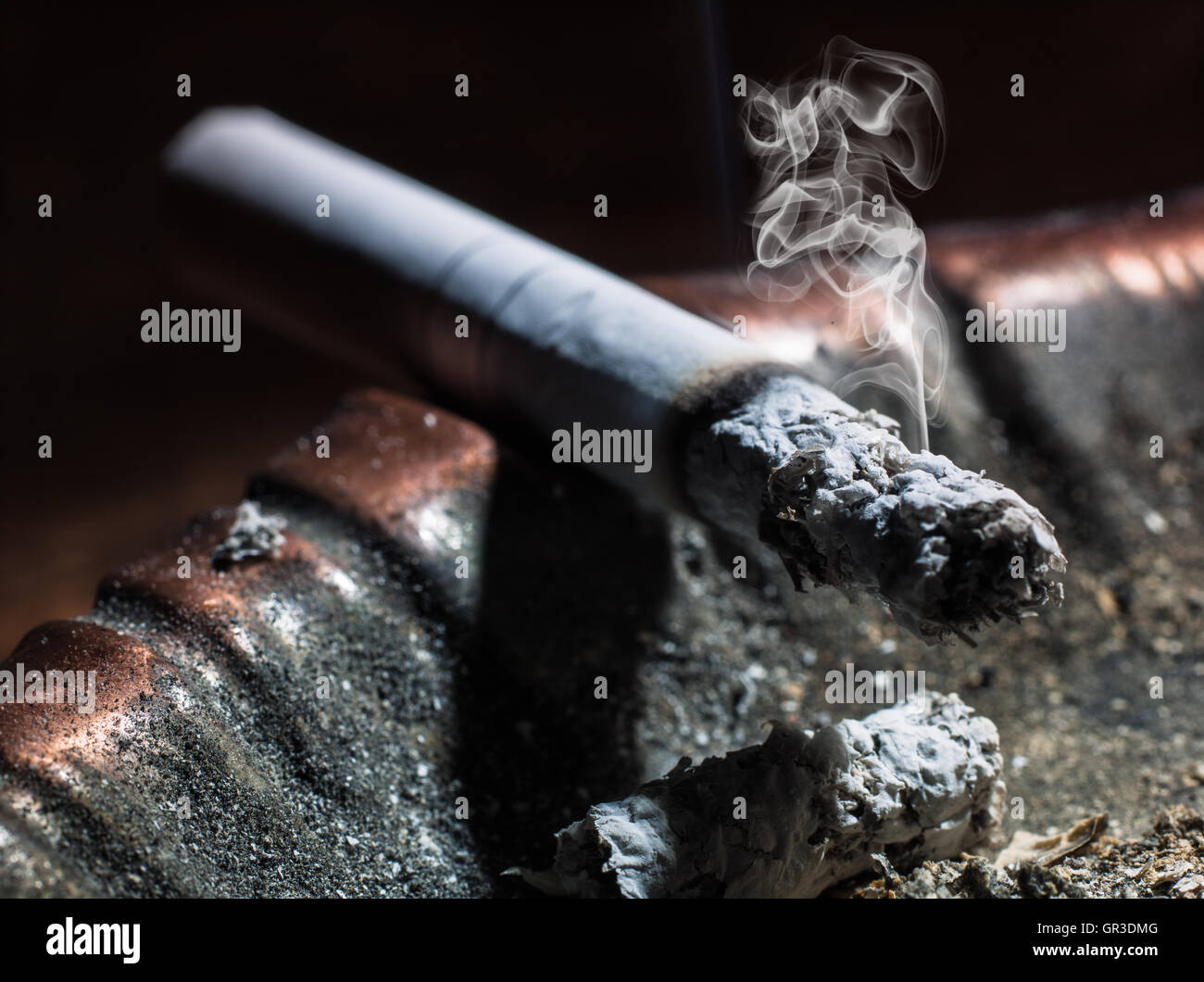 the cigarette emitting smoke burning in an ashtray Stock Photo
