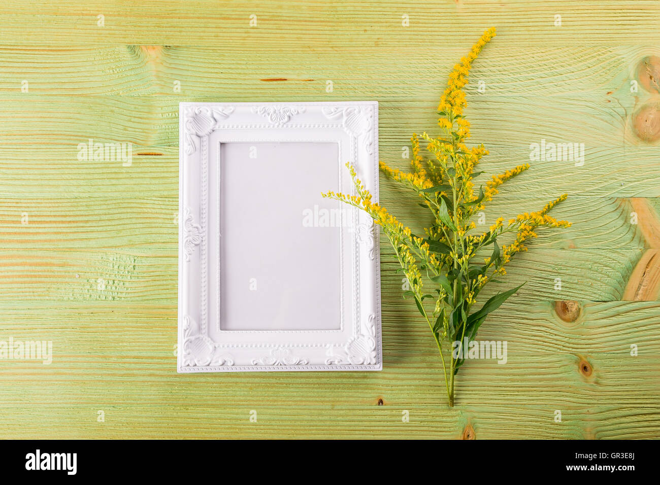 Craft mockup set with Yellow wild flowers and whitw photo frame on a light wooden table Stock Photo