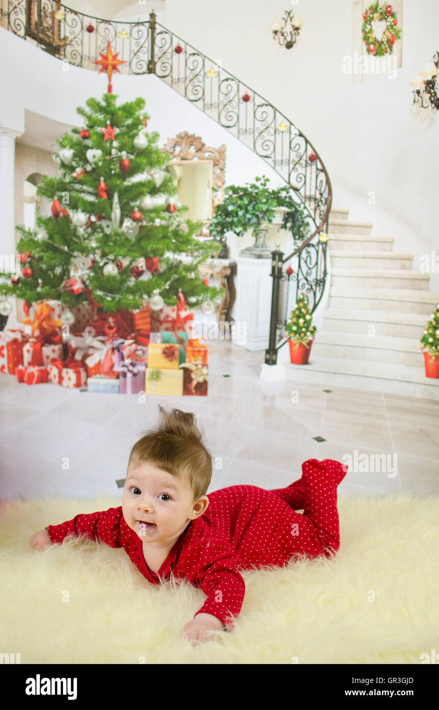 baby girl enjoying her first christmas with lots of gifts under