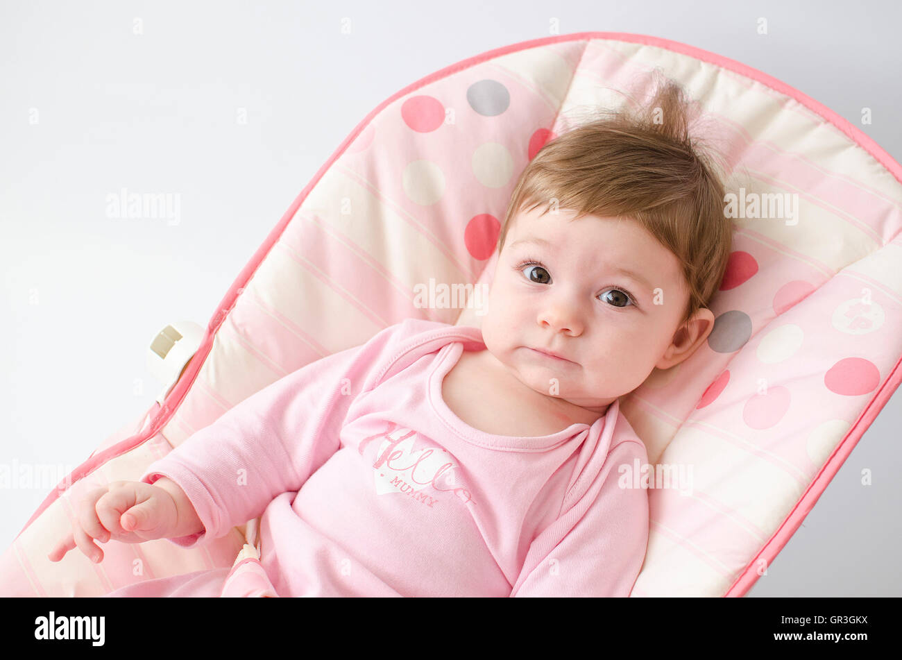 beautiful happy baby girl in a bouncer wearing pink onesie Stock Photo