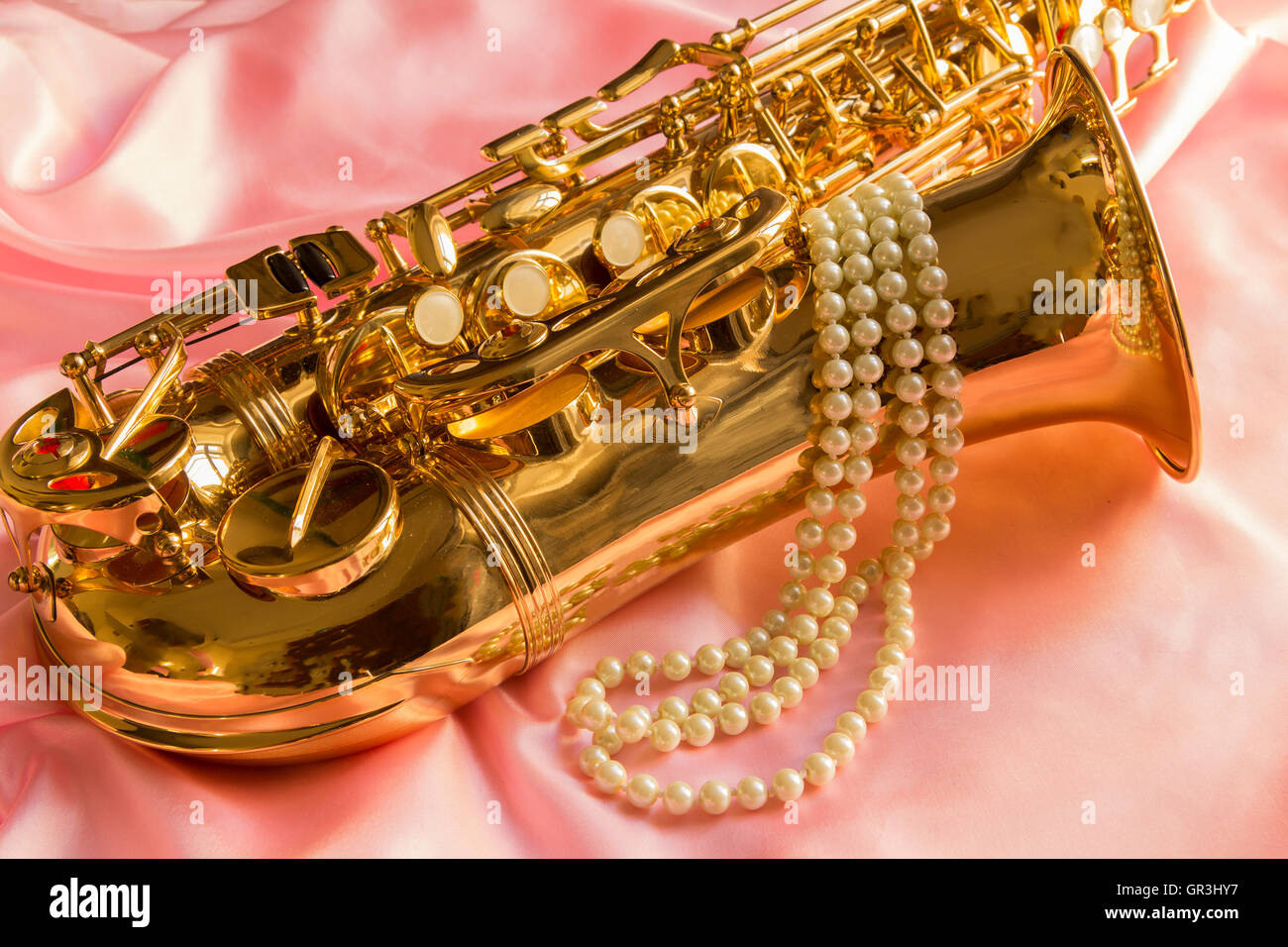 Saxophone and Pearl necklace on Pink silk Stock Photo