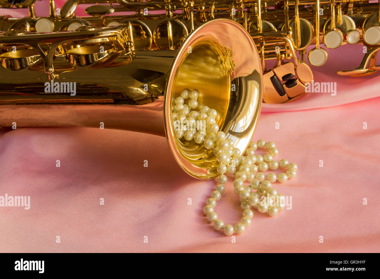 Saxophone and Pearl necklace on Pink silk Stock Photo