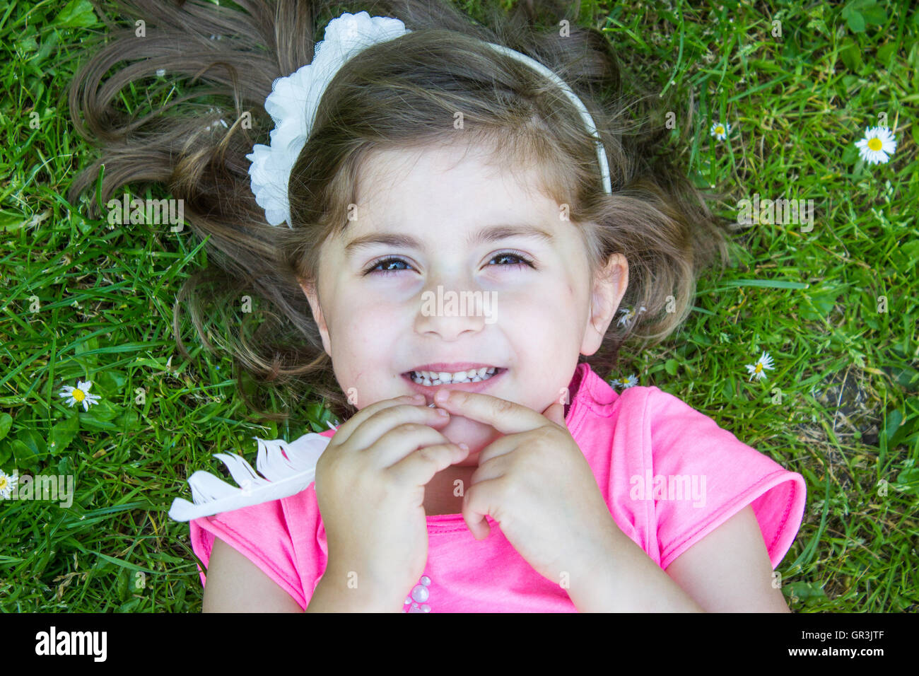 Little girl laying in the grass on a summer day Stock Photo - Alamy