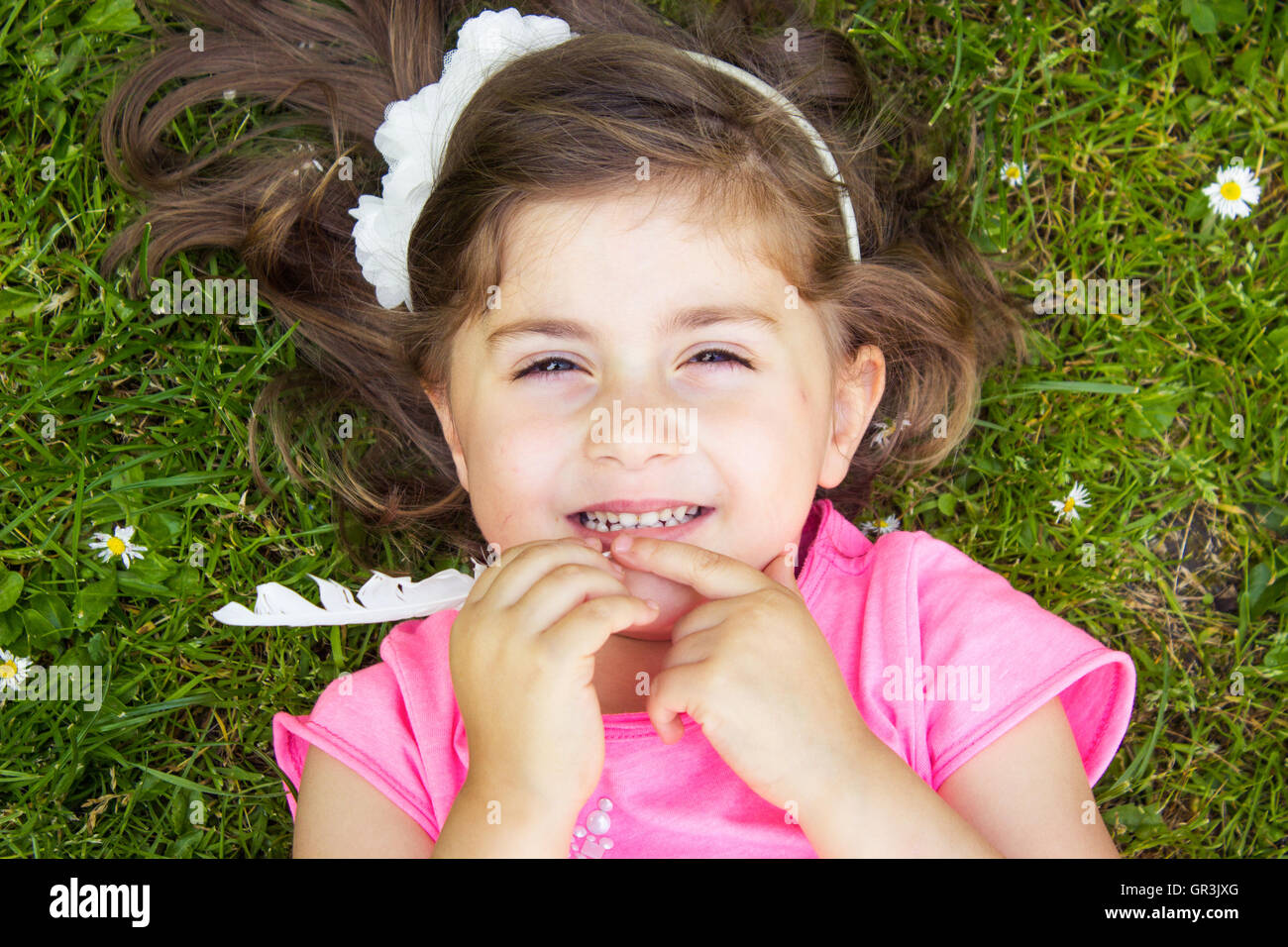 Little girl laying in the grass on a summer day Stock Photo