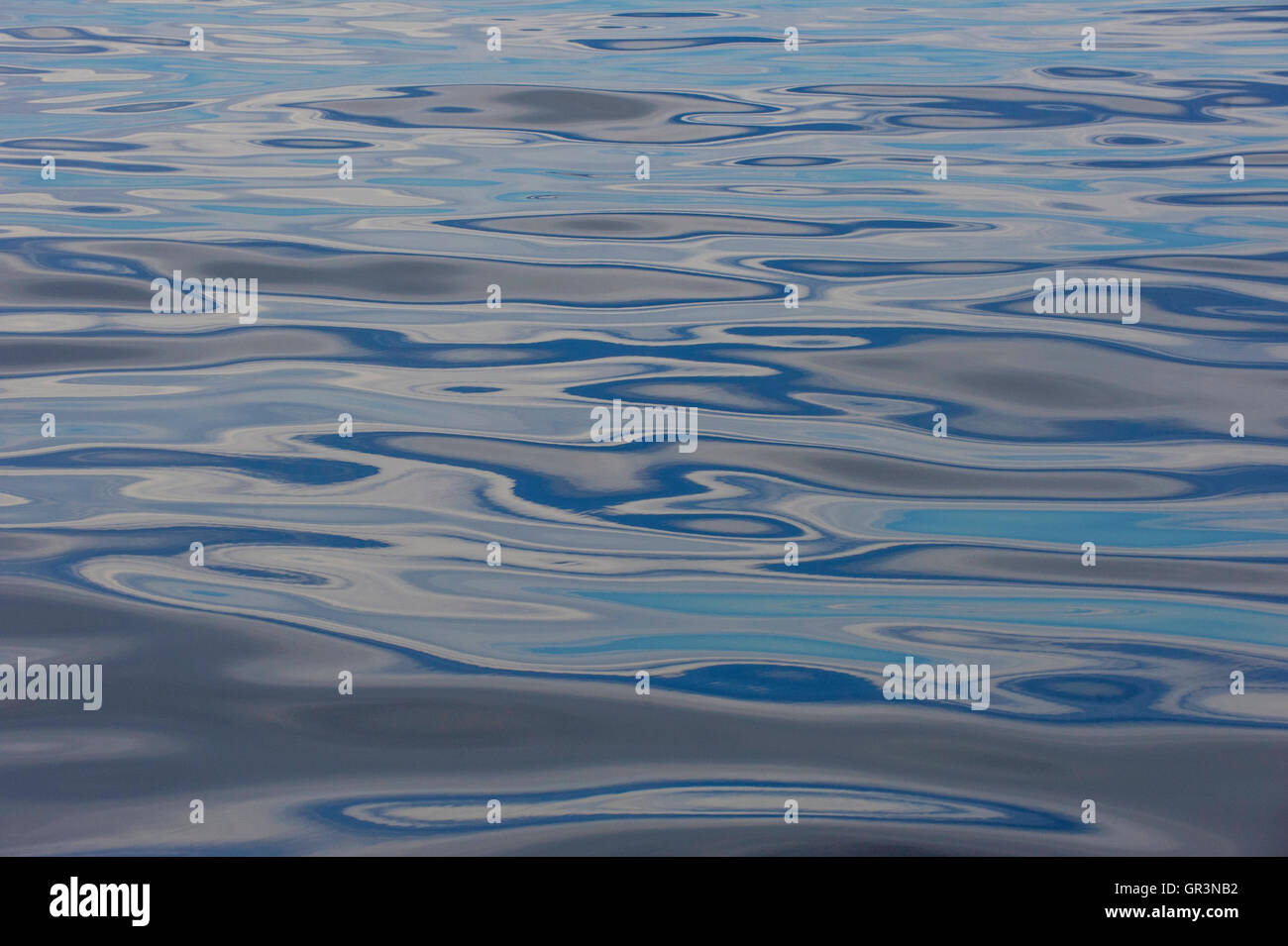 Blue sky and clouds are reflected on an incredibly calm Atlantic Ocean ...