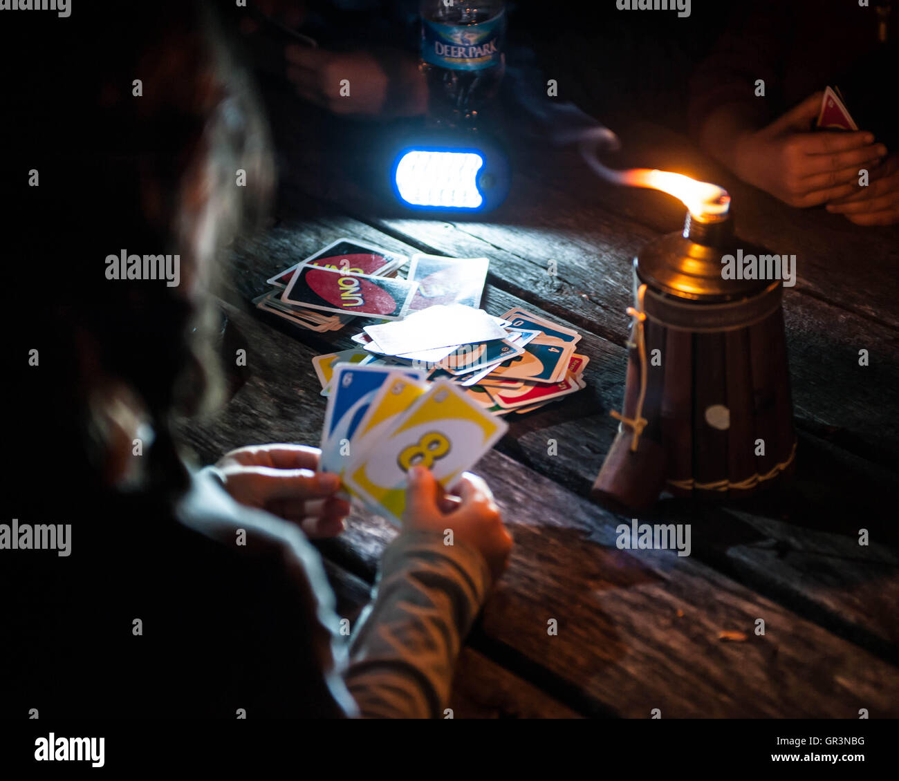 Kids play the card game Uno by an oil candle while Camping in French Creek State Park Pennsylvania Stock Photo