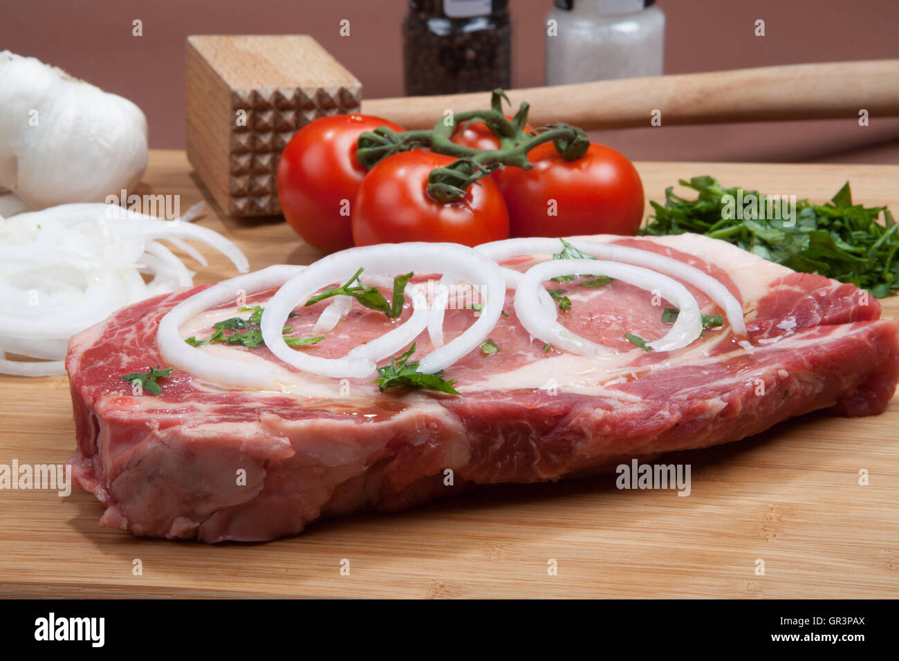 Rib Eye Steak,  chopping board,  meat, protein, beef, dinner,steak, marble, thick, isolated, onions, tomatoes on a vine Stock Photo