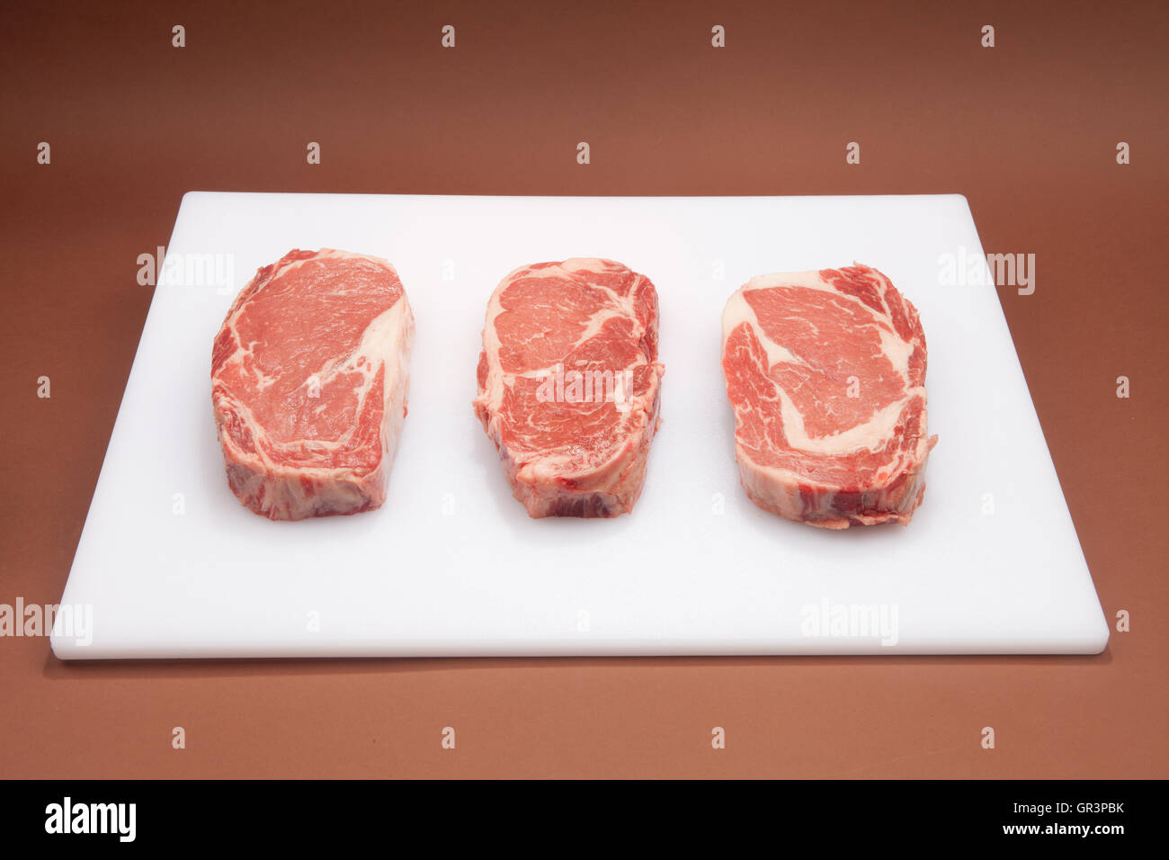 Rib Eye Steak on a white chopping board Stock Photo
