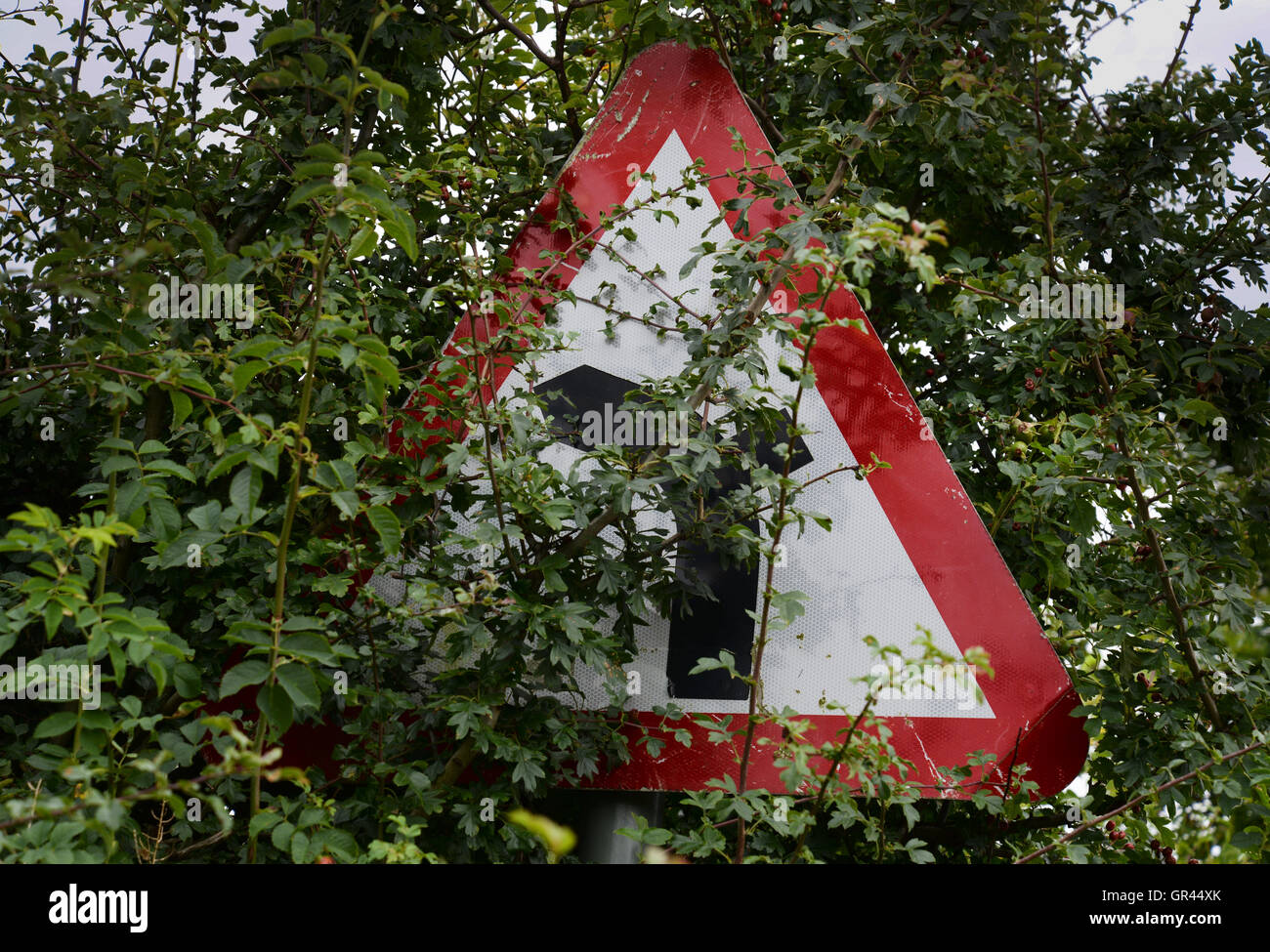 An obscured warning sign from the Highway Code, junction on bend ahead. Stock Photo