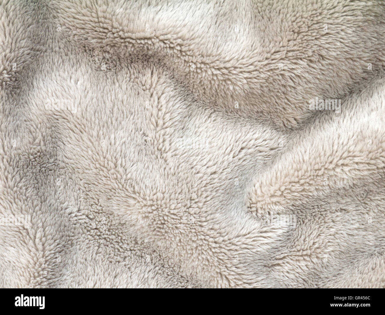 Beige folded fluffy polyester cozy fleece fabric background Stock Photo