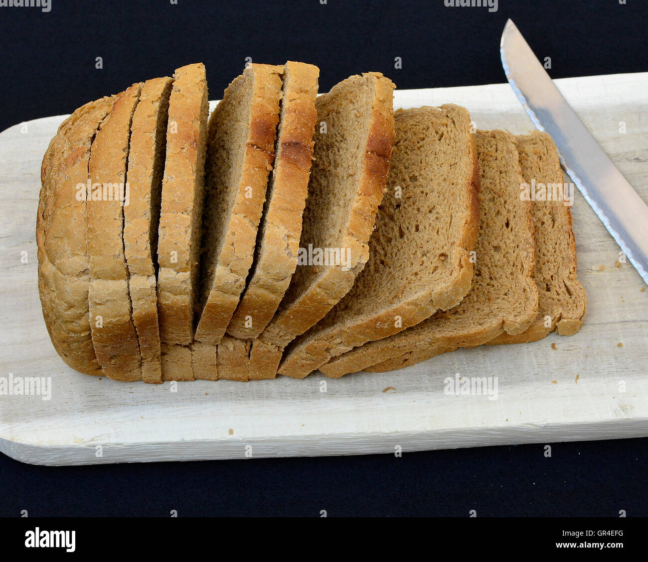 Freshly baked sliced brown rye bread on cutting board. Stock Photo