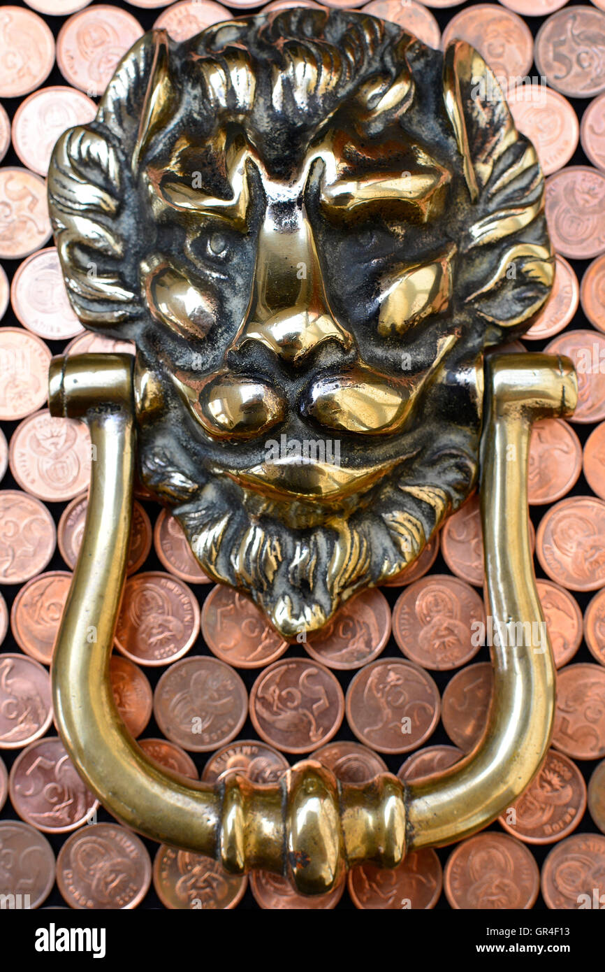 Opportunity knocking. Knocking for opportunity to profit. Brass lion head knocker on copper money. close up view. Stock Photo