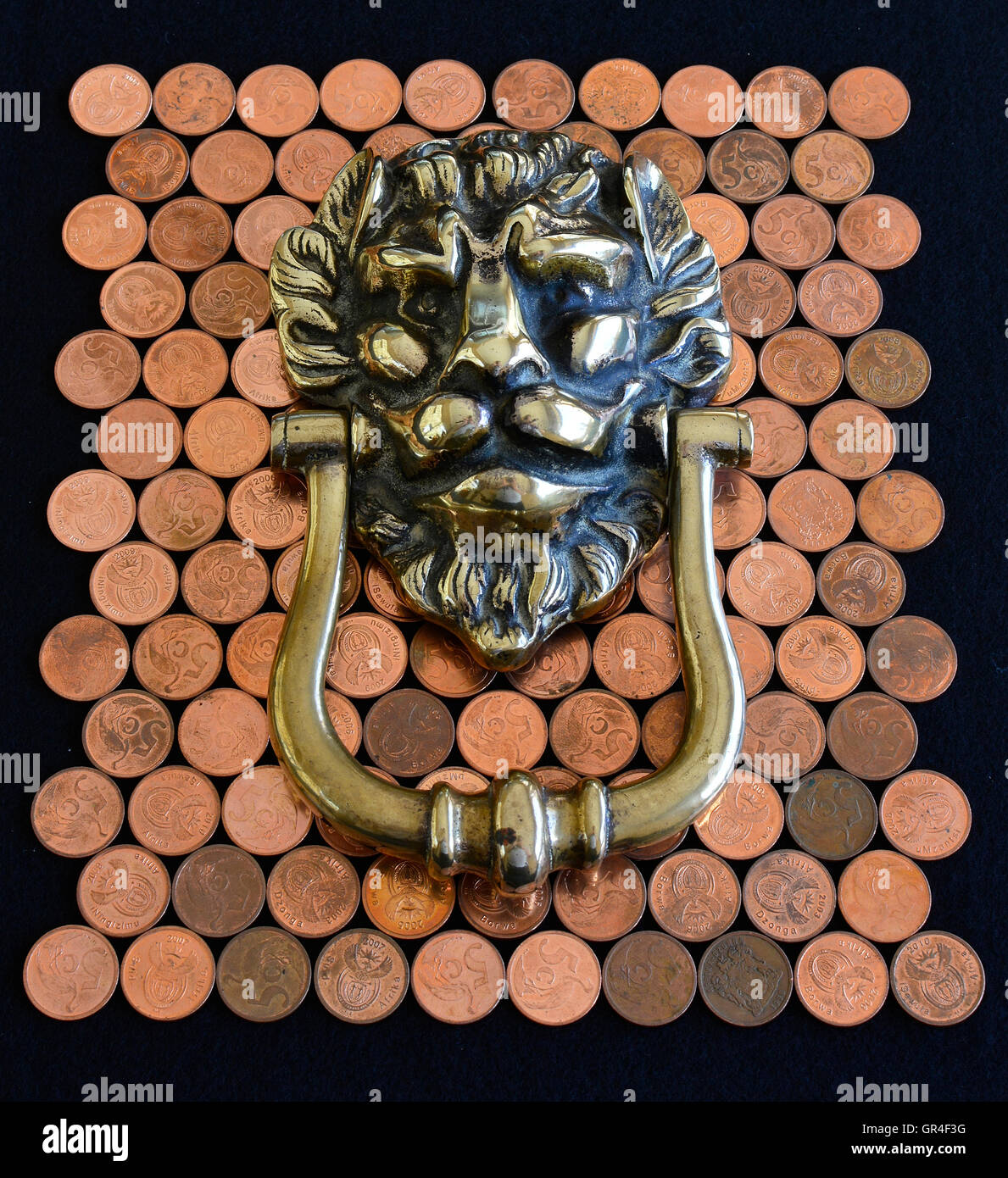 Opportunity knocking. Knocking for opportunity to profit. Brass lion head knocker on copper money. Full distant view. Stock Photo