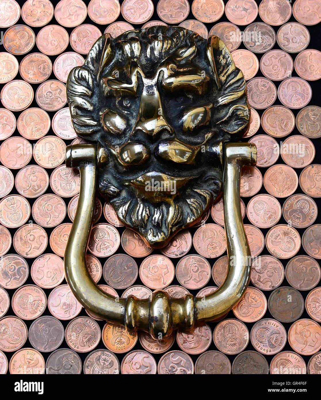 Opportunity knocking. Knocking for opportunity to profit. Brass lion head knocker on copper money. Full view. Stock Photo