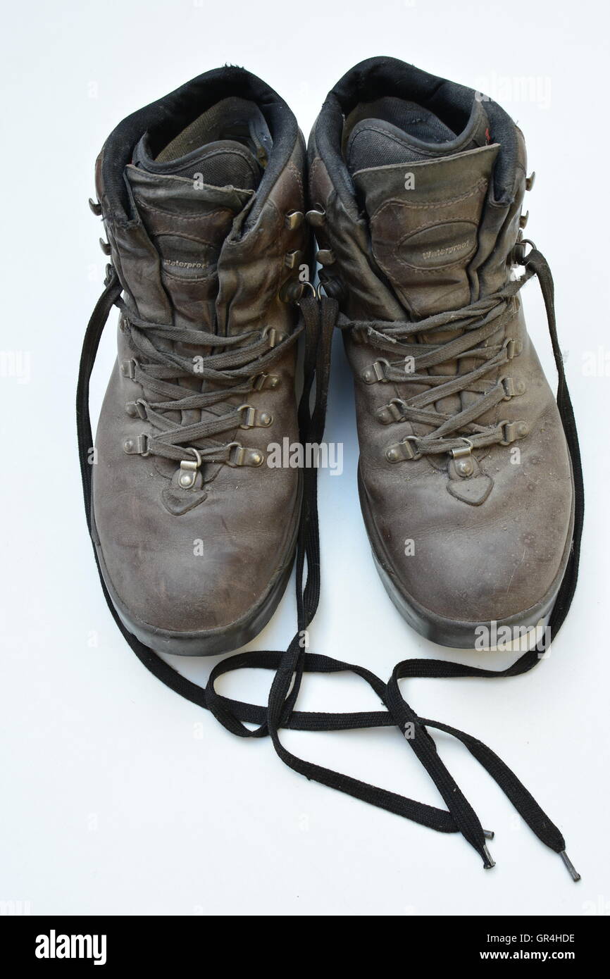 Dirty old boots isolated on white background hiking style. Bon voyage. Hiking style used boots, it was a great trip. Laces wild. Stock Photo