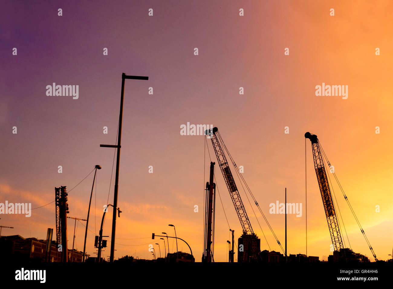 Cranes silhouettes of subway line over colorful sunset sky Stock Photo