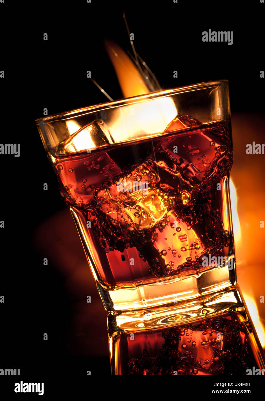 cola with whiskey in glass and fire on black Stock Photo