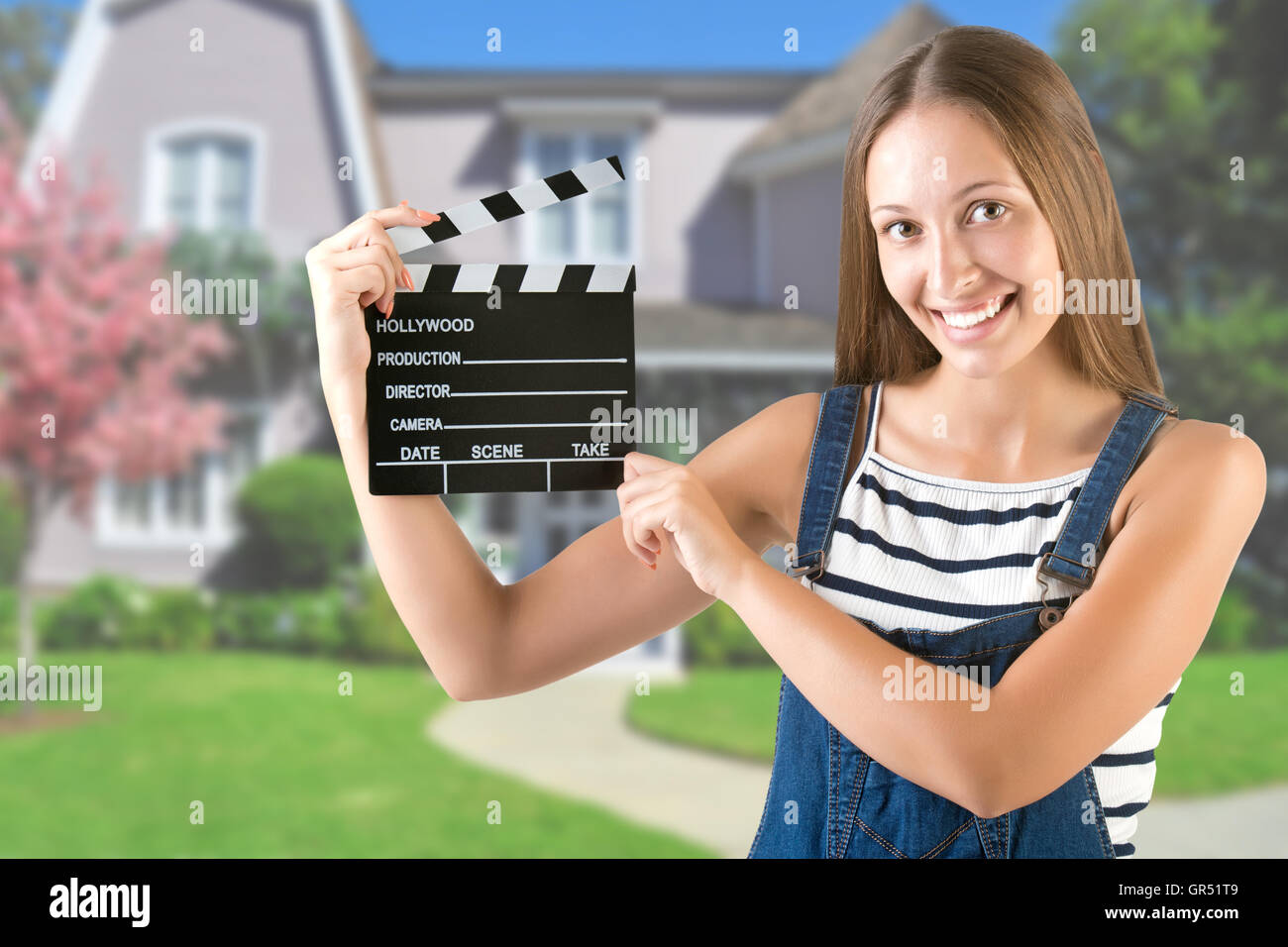 Woman holding a clapperboard, with a house in the background Stock Photo