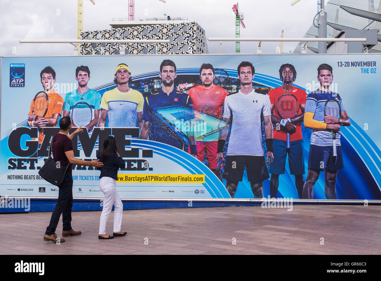 Couple watching a giant billboard promoting the Barclays ATP World Tour Finals 2016 which will be held in London 13-20 November Stock Photo