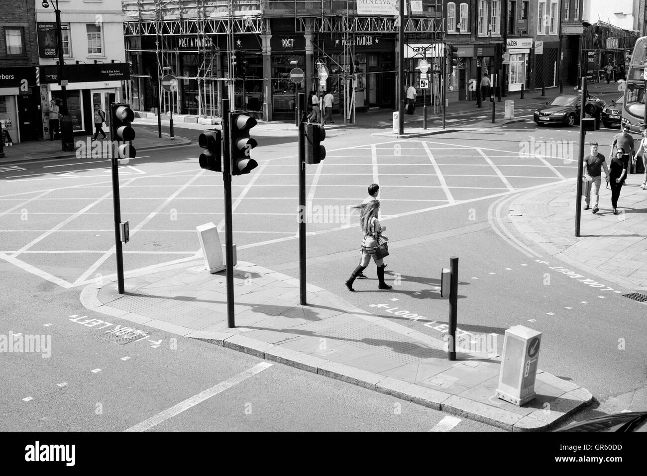 - 10 July 2016: Couple crossing the road at a pedestrian crossing with traffic lights in Shoreditch, East London. Stock Photo
