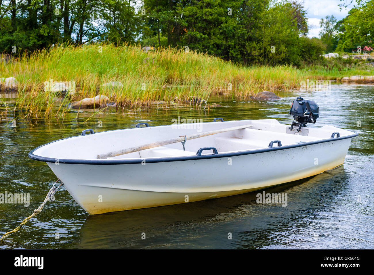 Small open motorboat or rowboat moored in shallow bay with reed in background. Stock Photo