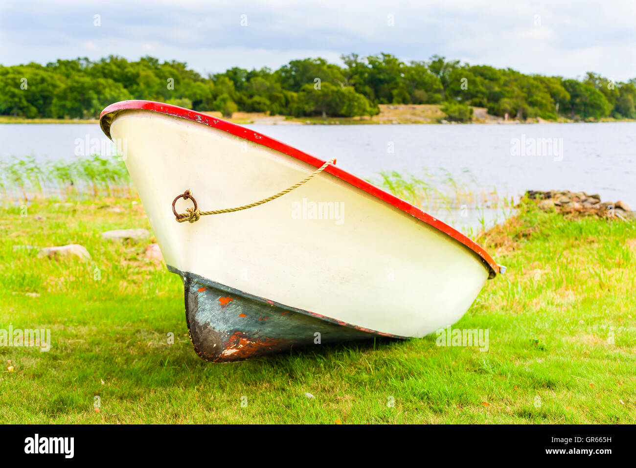 Red and yellowish white plastic rowboat lying on land. Stock Photo