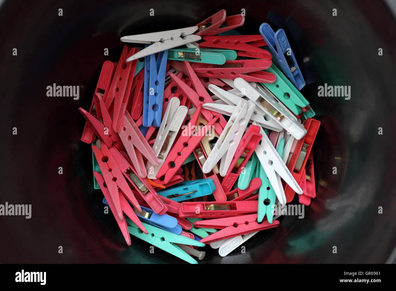 Mixed colour clothes pegs against black Stock Photo