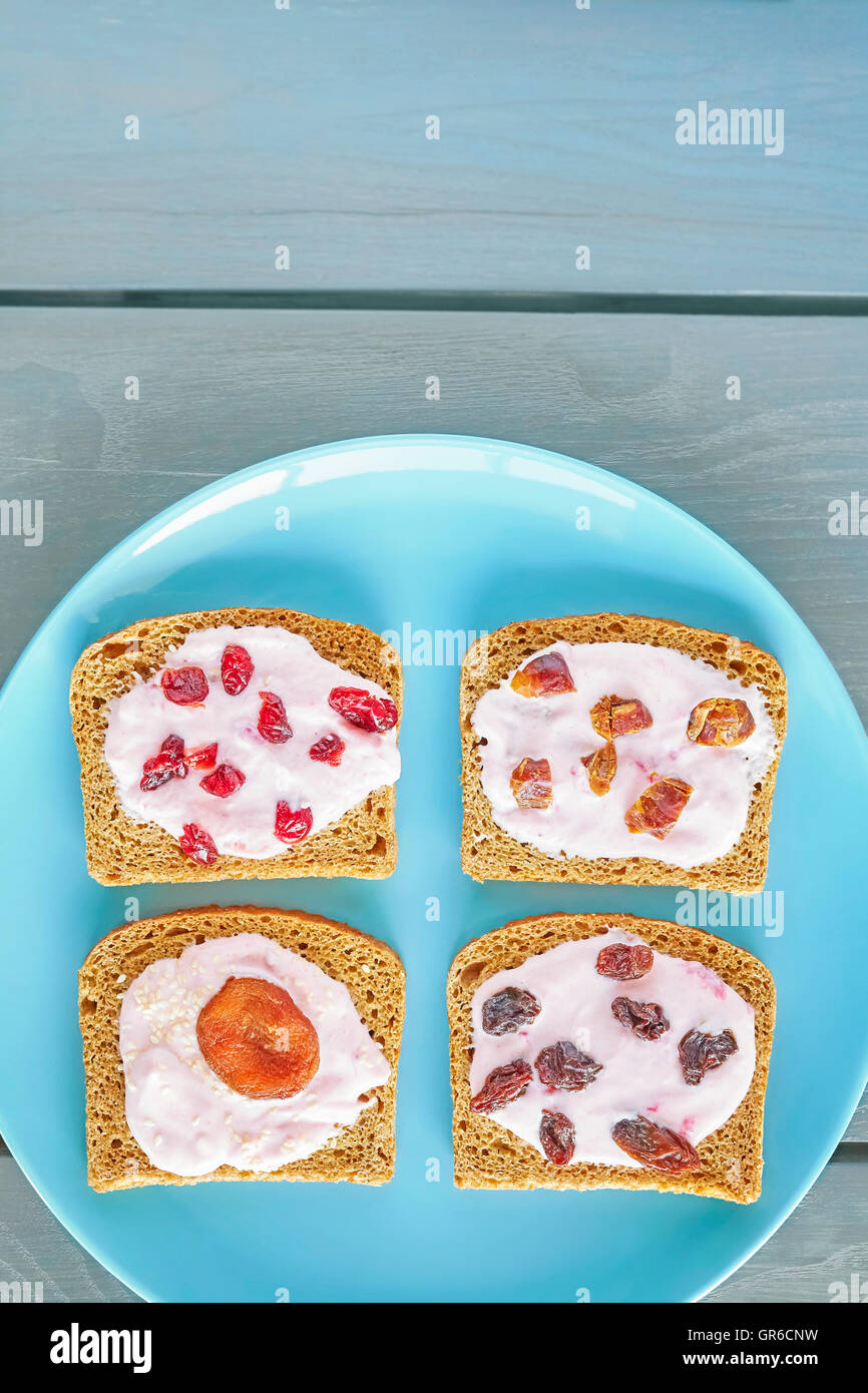 Bread with strawberry cream cheese and dry fruits on blue plate