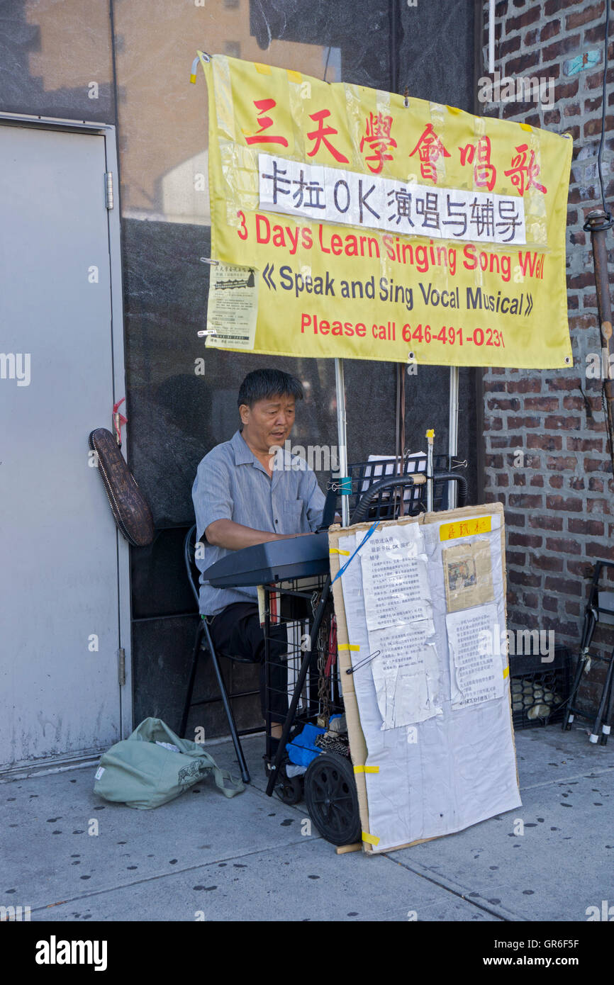 A Korean man playing the piano on Main Street in Flushing advertising singing lessons Stock Photo