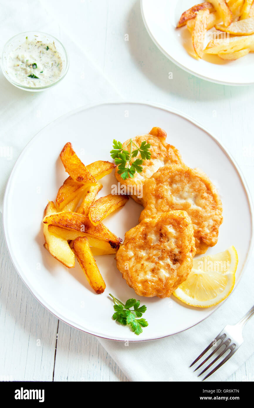 Homemade fish cakes with french fries on white plate close
