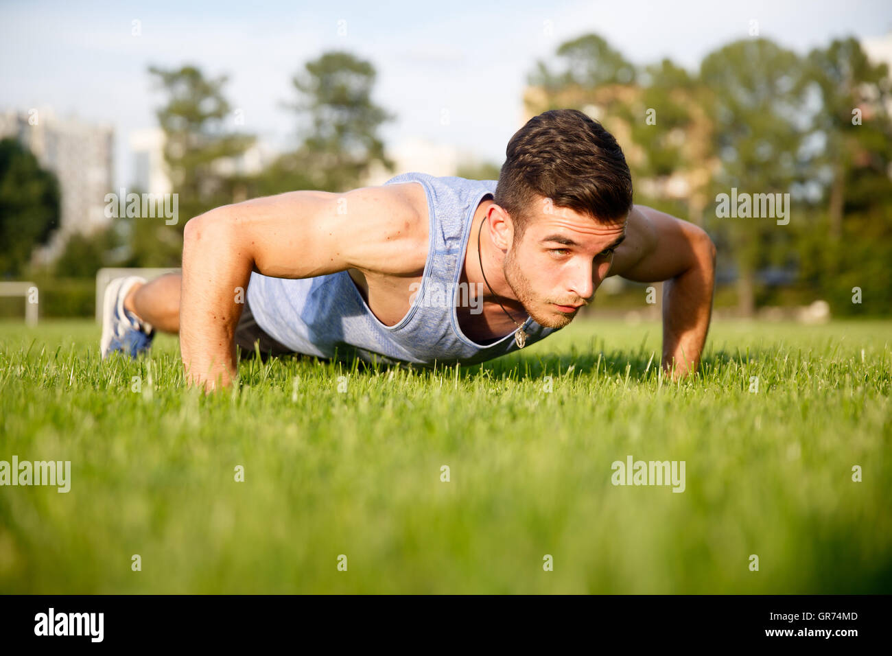 young athlete doing push-ups on grass Stock Photo