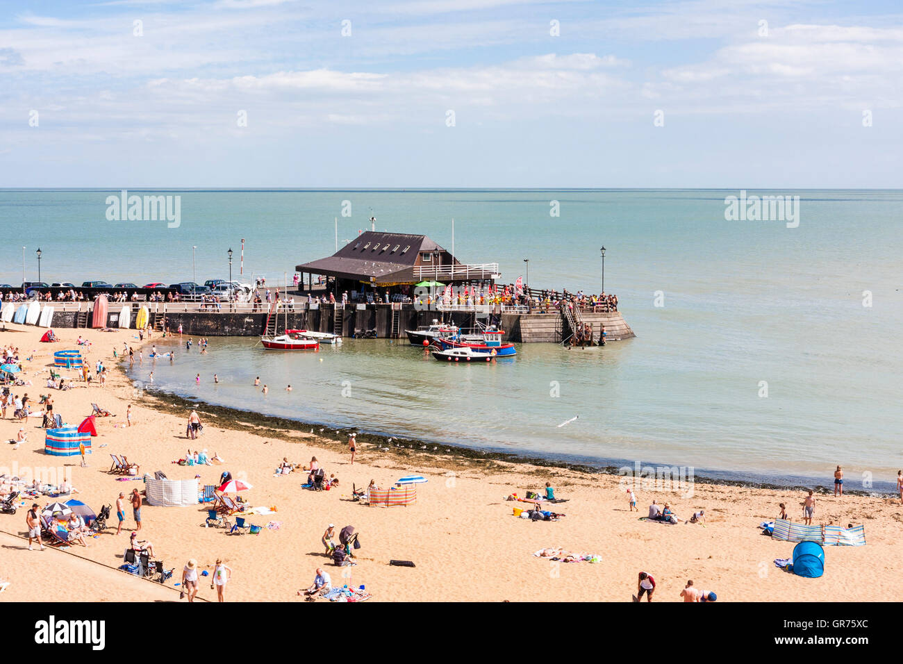 Broadstairs resort town in UK, the main beach with small harbour at one end. Hot summer day with lots of people and families on beach sunbathing. Stock Photo