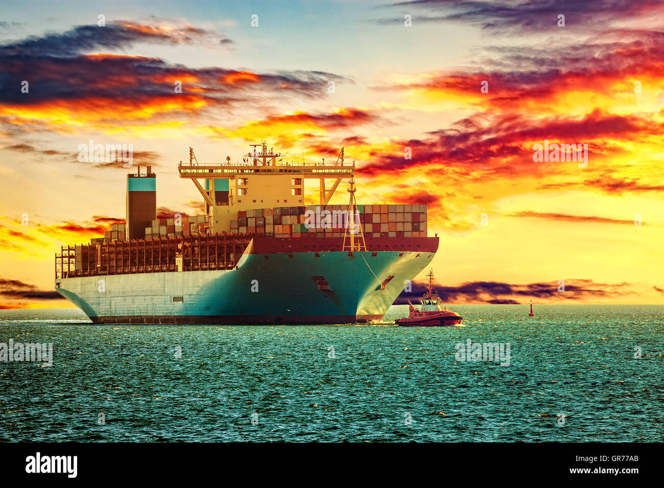 Tugboat assisting container ship on sea in the morning. Stock Photo