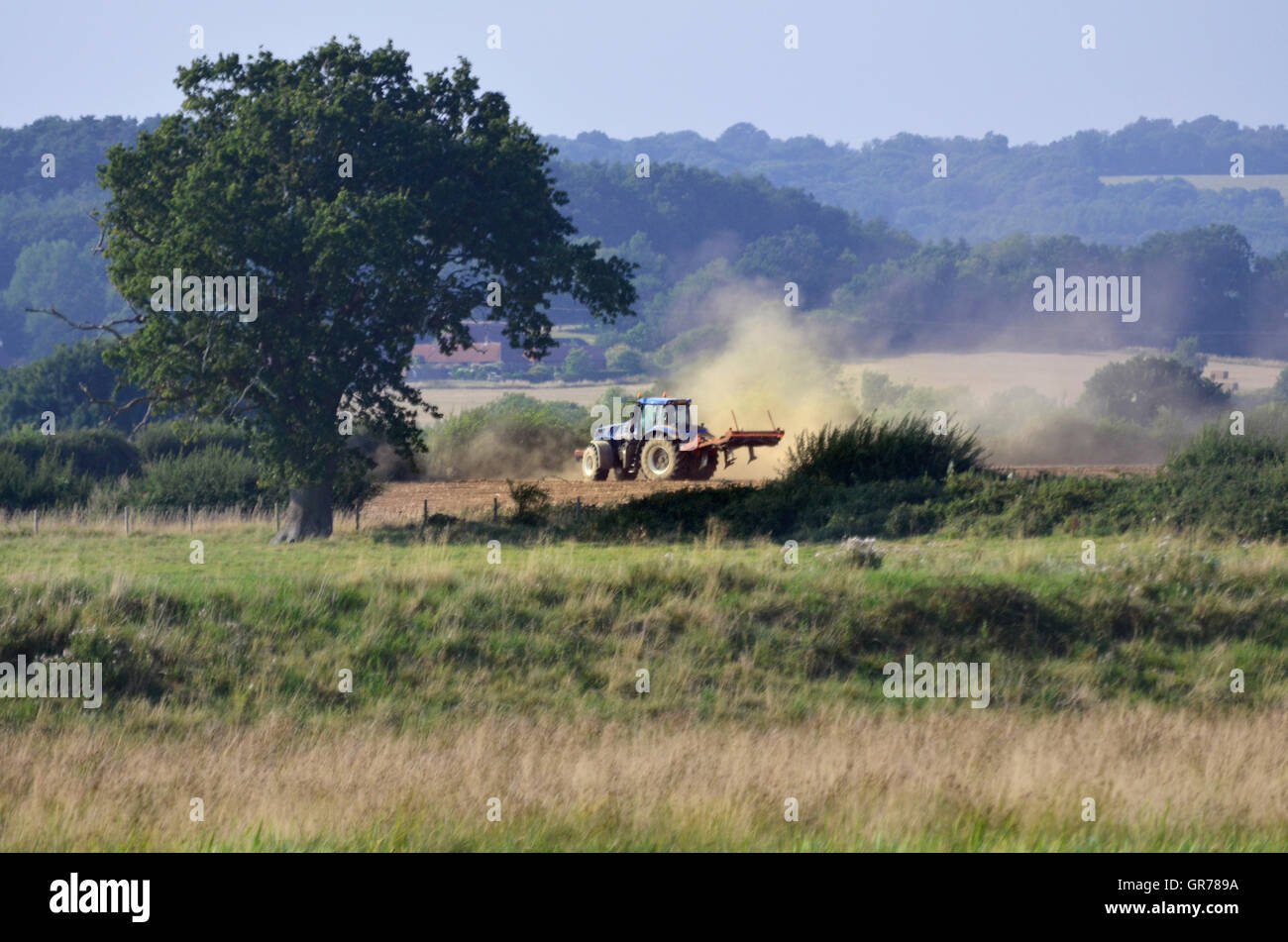 tractor cultivating dry and dusty field Stock Photo