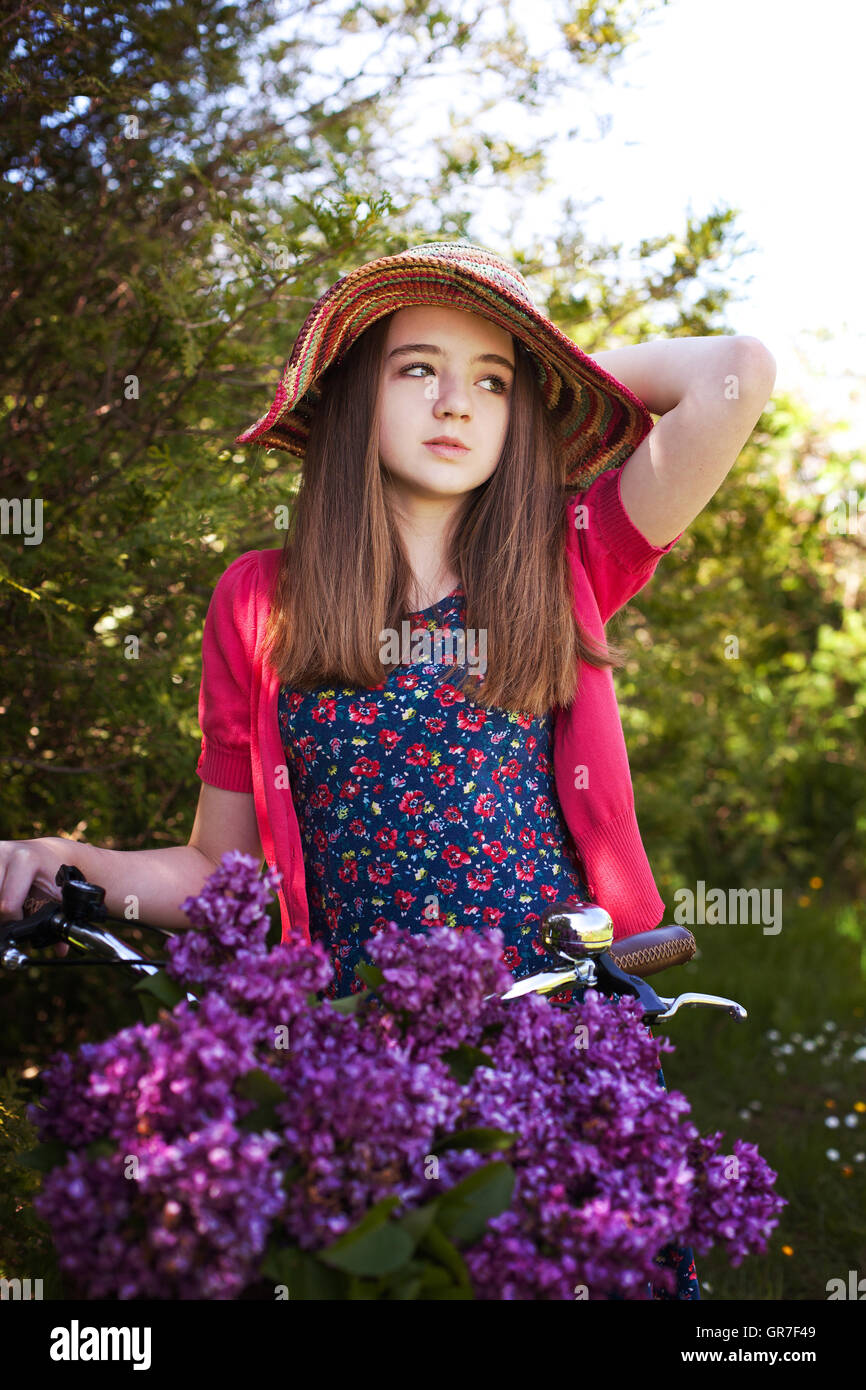 Beautiful teenage girl sitting on a bicycle with a basket of purple ...