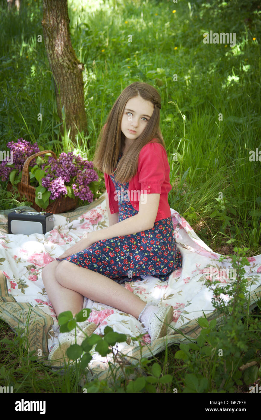 Beautiful teenage girl sitting on a blanket in a woodland Stock Photo