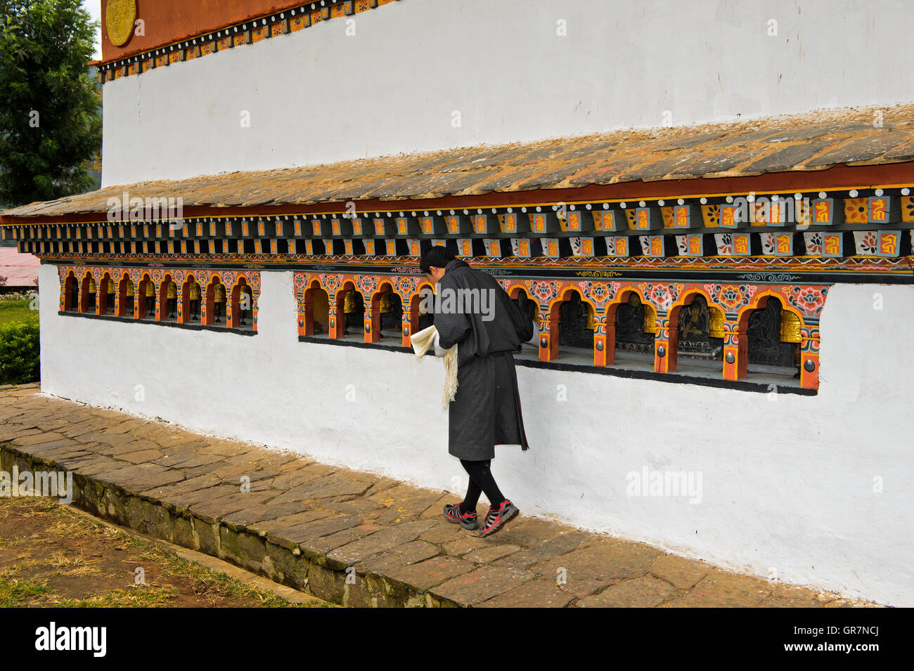 Young Local Man Turning Prayer Mills, Monastery Chime Lhakhang Near Lobesa, Bhutan Stock Photo