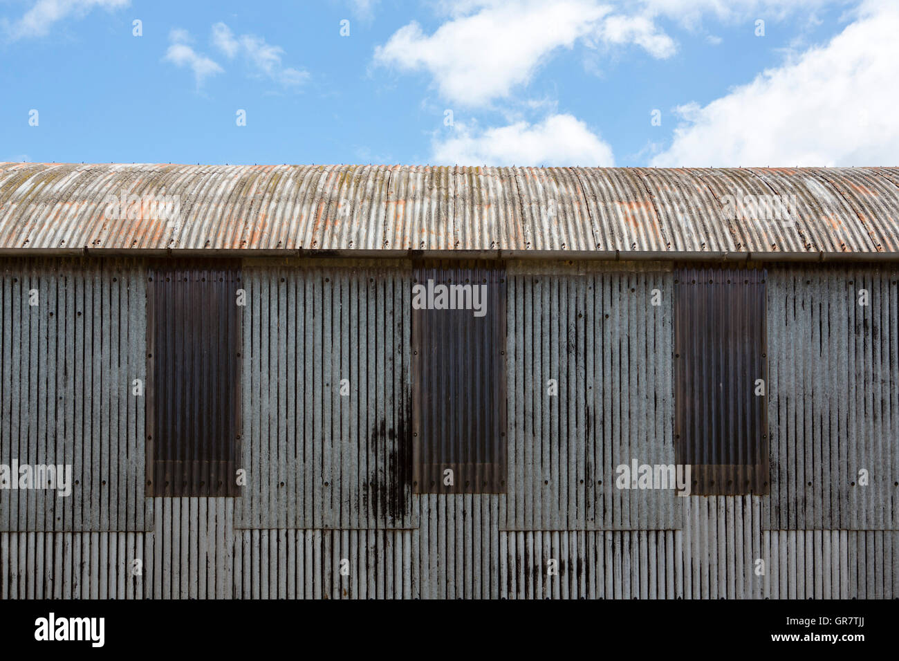 Old corrugated iron barn on a farm with weathered rusty surface adn ...