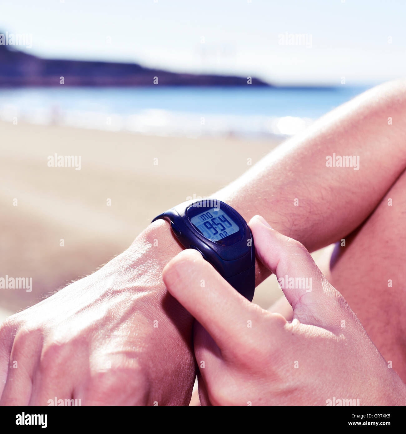 closeup of a young sportsman syncing his smartwatch, with the sea in the background Stock Photo