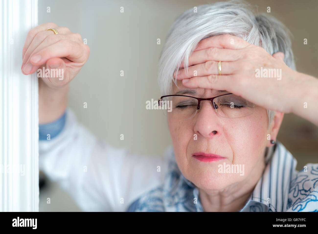 An Elderly Lady With A Headache Holds His Hand To His Forehead. Stock Photo