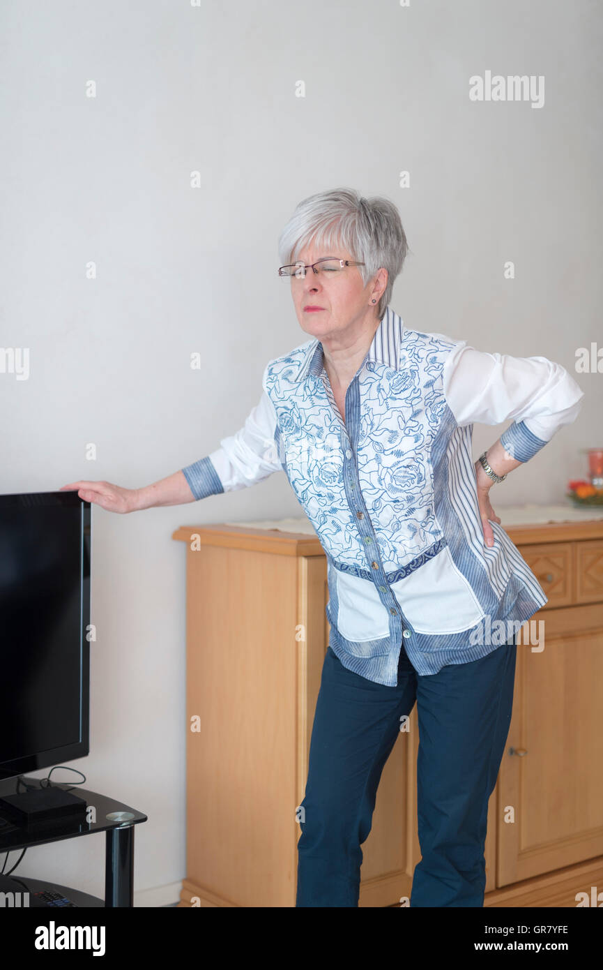 One Senior Has Back Pain And Is Based On The Television On. Stock Photo