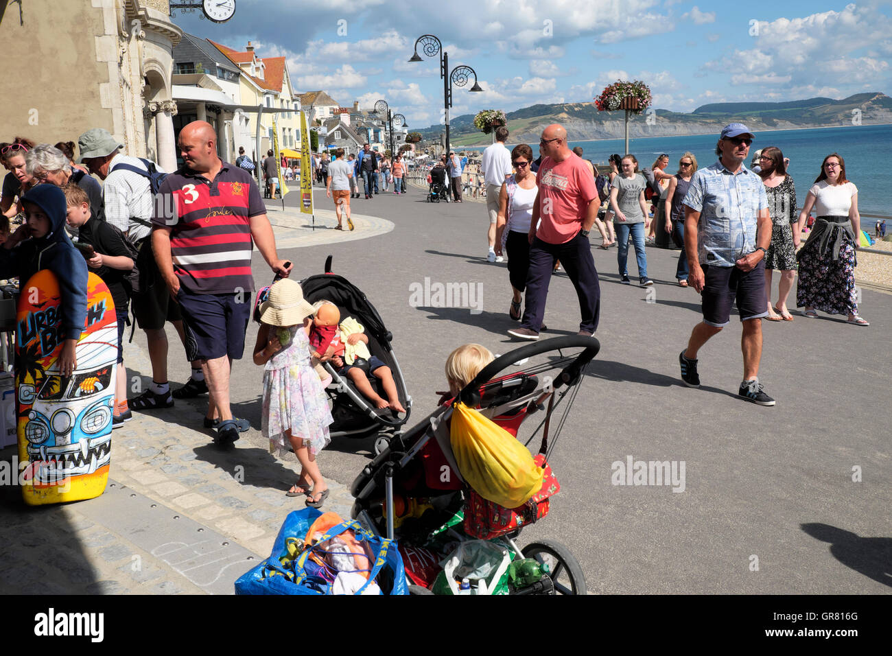 People on holiday look in shops on 'Marine Parade'  by the waterfront beach area at Lyme Regis, Dorset, England UK   KATHY DEWITT Stock Photo