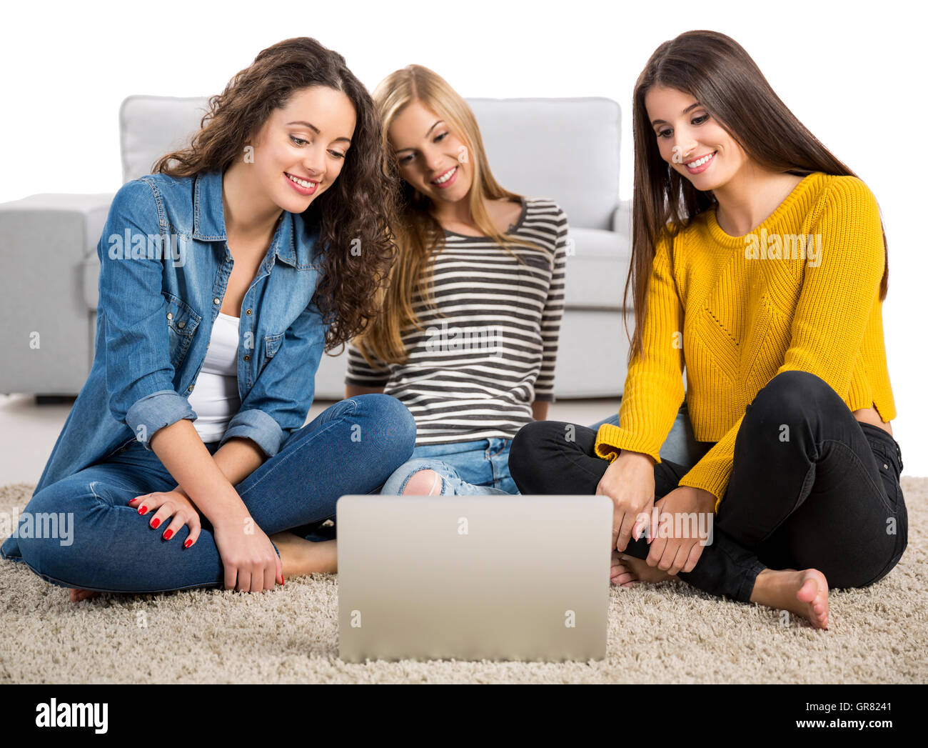 Happy teen girls studying at home with a laptop Stock Photo