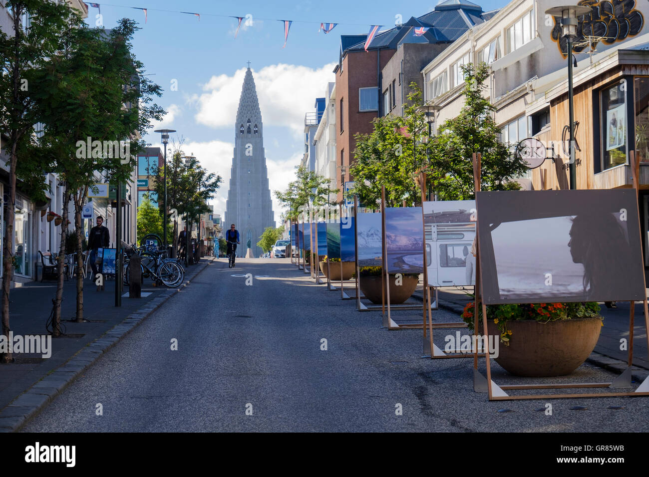 Street scene with paintings on display and Lutheran Parish Church Hallgrímskirkja on hilltop. Skolavordustigur Reykjavik Iceland Stock Photo