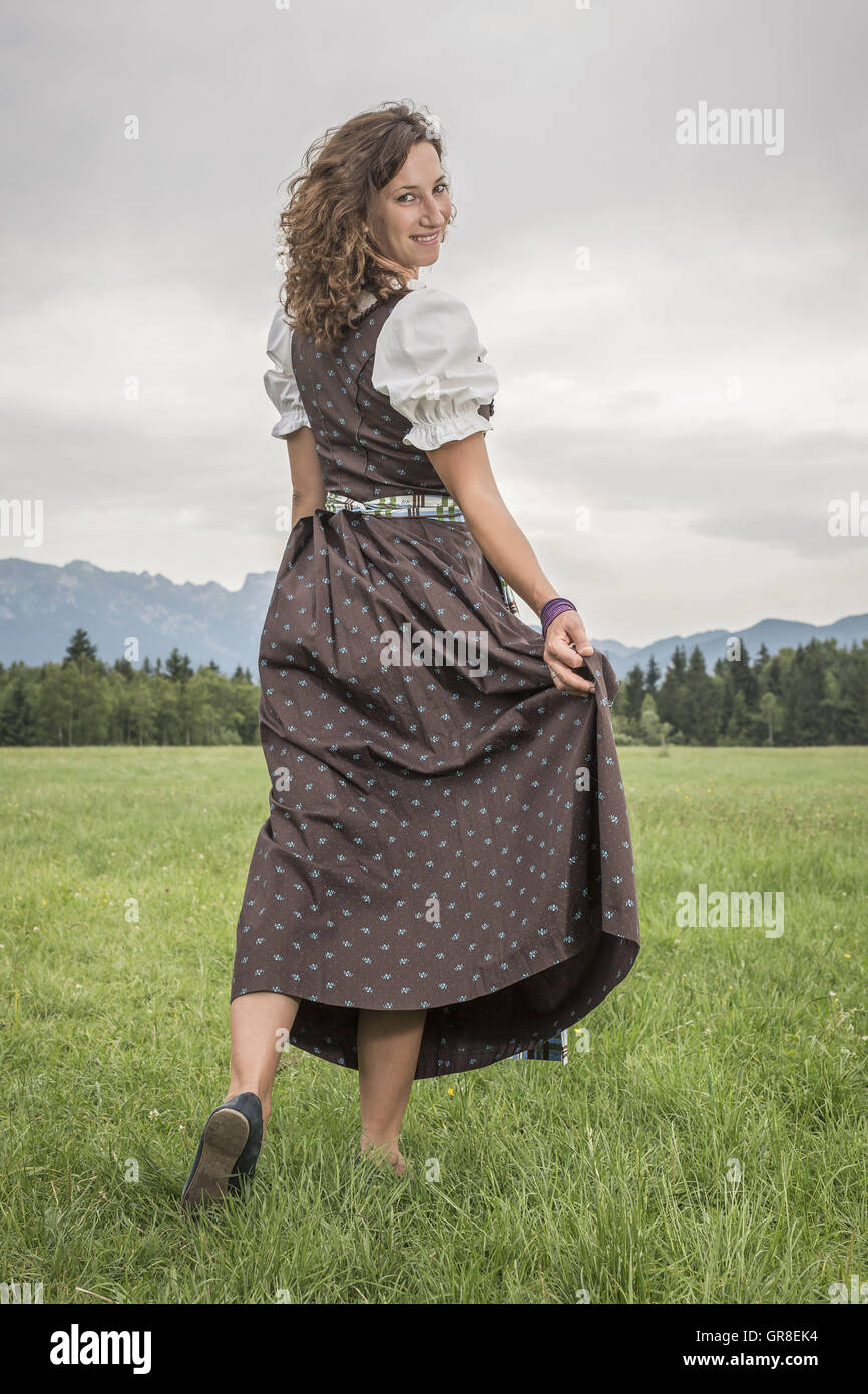 Woman In Dirndl Goes With Flowing Skirt Over A Green Meadow Stock Photo Alamy